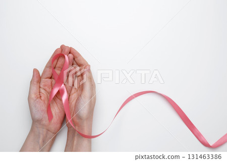 Female hand holding pink ribbon symbol of breast cancer awareness Female hand holding pink ribbon symbol of breast cancer awareness 131463386