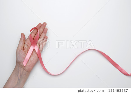 Female hand holding pink ribbon symbol of breast cancer awareness 131463387
