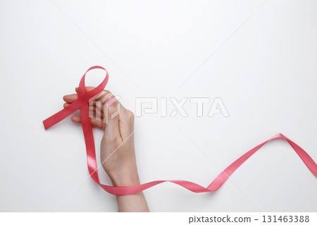 Female hand holding pink ribbon symbol of breast cancer awareness 131463388