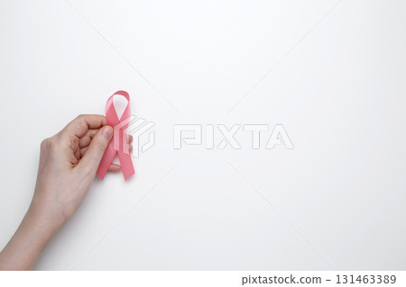 Female hand holding pink ribbon symbol of breast cancer awareness 131463389