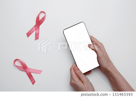 Woman using smartphone to schedule doctor appointment with pink ribbon breast cancer awareness 131463393