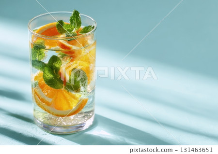 Glass of infused water with orange slices and mint leaves soft summer light clean background 131463651