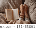 Girl on bed with open book and wool socks 131463801
