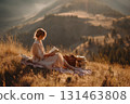 Girl in linen dress reading on hill picnic 131463808