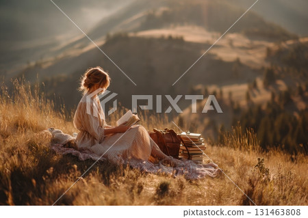 Girl in linen dress reading on hill picnic Girl in linen dress reading on hill picnic 131463808