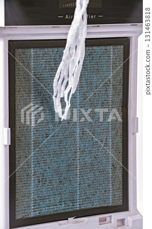 Image shows air purifier filter with piece of tissue demonstrating its suction power. filter appears to be in use, capturing dust and particles.air purifier filter showing suction power Image shows air purifier filter with piece of tissue demonstrating its suction power. filter appears to be in use, capturing dust and particles.air purifier filter showing suction power 131463818