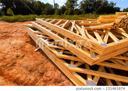 Stacked wooden beams roofing joints are placed on construction site under works day with trees in dirt ground. Stacked wooden beams roofing joints are placed on construction site under works day with trees in dirt ground. 131463874