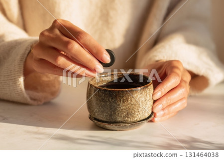 Woman preparing shilajit supplement in ceramic cup with warm water wellness vibe 131464038