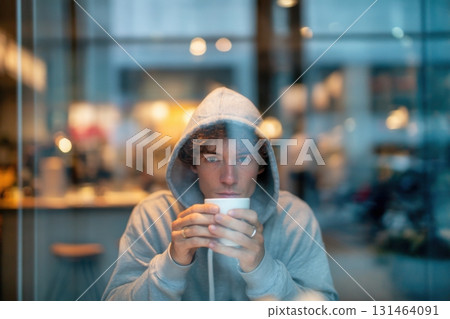 Young man in hoodie inside modern cafe interior 131464091