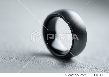 Modern matte black smart ring with integrated biometric sensors on finger close-up Modern matte black smart ring with integrated biometric sensors on finger close-up 131464096
