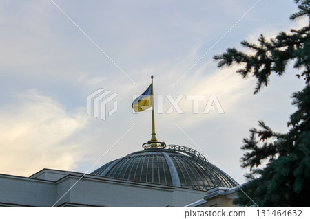 Ukrainian flag, with vibrant blue and yellow colors, proudly flies atop a domed government building, symbolizing national identity, sovereignty, and state power 131464632