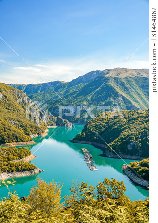 Aerial view of Piva Lake surrounded by high mountains in Montenegro, with scenic natural landscape and blue water Aerial view of Piva Lake surrounded by high mountains in Montenegro, with scenic natural landscape and blue water 131464862