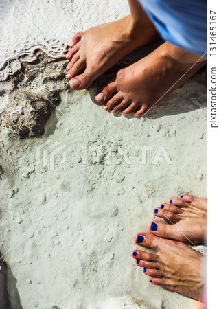 Two pairs of bare feet standing on white mineral terraces with water. Travel lifestyle, vacation concept and natural wellness background Spa and relax Two pairs of bare feet standing on white mineral terraces with water. Travel lifestyle, vacation concept and natural wellness background Spa and relax 131465167
