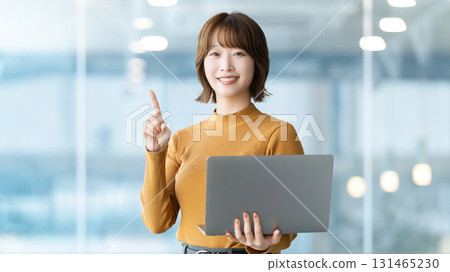 A smiling woman/businesswoman giving directions while holding a computer A smiling woman/businesswoman giving directions while holding a computer 131465230