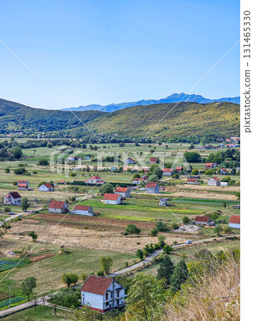 Aerial view of fields with scattered houses in a valley, surrounded by mountains, showcasing scenic rural landscape and traditional lifestyle, ideal for travel, nature, and lifestyle projects 131465330