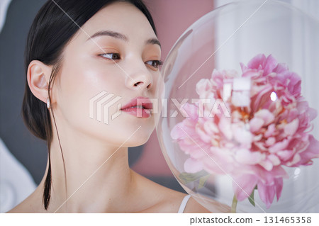 Woman with long black hair and a pink flower in a glass 131465358