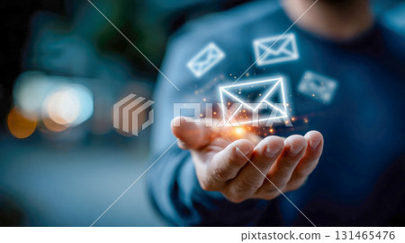 Businessman holding holographic glowing email icons representing digital communication and notifications 131465476