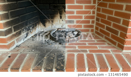 Close up view of a brick fireplace hearth divided in two. One side shows soot build-up while the other side is freshly restored and clean, highlighting the transformation. 131465490