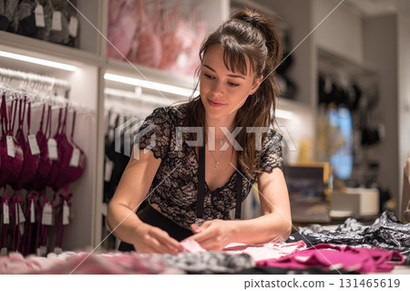 A sales assistant packs underwear in a lingerie store. Product sales concept. Consultant assistance in choosing. 131465619