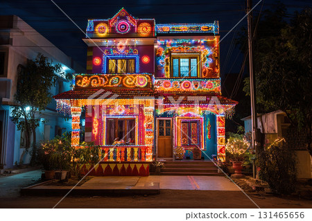 The two-story house is brightly illuminated with colorful garlands outside. Indian and Asian holidays. Decorating the house for seasonal celebrations. 131465656