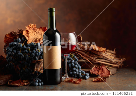 Bottle of red wine with blue grapes on a brown background. Bottle of red wine with blue grapes on a brown background. 131466251
