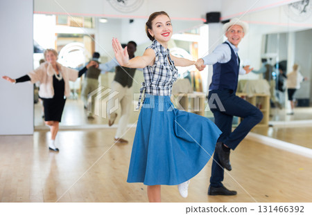 Cheerful female practicing lindy hop in pair with man Cheerful female practicing lindy hop in pair with man 131466392