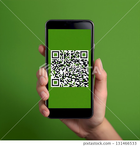 Person scanning a QR code with a smartphone against a green background during daylight hours 131466533