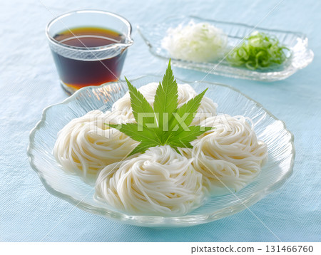 Somen noodles served in a clear glass bowl decorated with blue maple leaves and topped with condiments and cold mentsuyu sauce. Somen noodles served in a clear glass bowl decorated with blue maple leaves and topped with condiments and cold mentsuyu sauce. 131466760