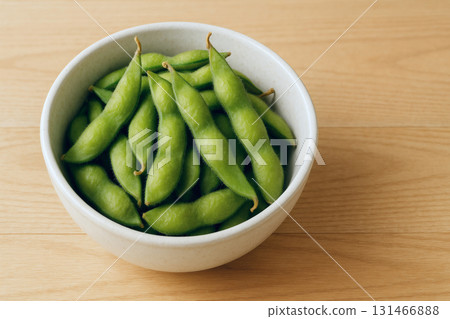 木桌上放著白色陶瓷碗的新鮮綠色毛豆特寫食物照片 131466888