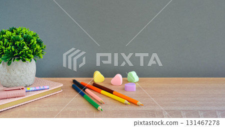 On the wooden surface of the table lies a notebook with a pen, marker, pencils and erasers. On the wooden surface of the table lies a notebook with a pen, marker, pencils and erasers. 131467278