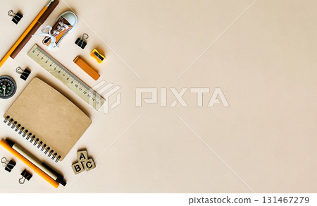 On a beige background there are stationery, pens, sneakers, a brown notebook, an eraser, a compass, a ruler, a pencil sharpener On a beige background there are stationery, pens, sneakers, a brown notebook, an eraser, a compass, a ruler, a pencil sharpener 131467279