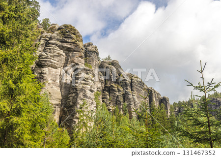 Adrspach-Teplice Rocks, sandstone formations in Hradec Kralove Region in Czech Republic, Europe. Scenic view of impressive rock formations, standing tall amidst the lush greenery, under a cloudy sky. 131467352