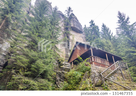 Landscape of Adrspach-Teplice Rocks area, in Hradec Kralove Region in Czech Republic, Europe. Wooden cabin nestled amidst towering rock formations and lush evergreen trees in tranquil natural setting. Landscape of Adrspach-Teplice Rocks area, in Hradec Kralove Region in Czech Republic, Europe. Wooden cabin nestled amidst towering rock formations and lush evergreen trees in tranquil natural setting. 131467355