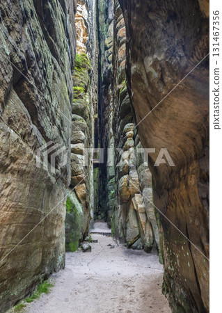 Adrspach-Teplice Rocks, sandstone formations in Hradec Kralove Region in Czech Republic, Europe. A narrow pathway cuts through towering rock formations, inviting exploration of this natural wonder. 131467356