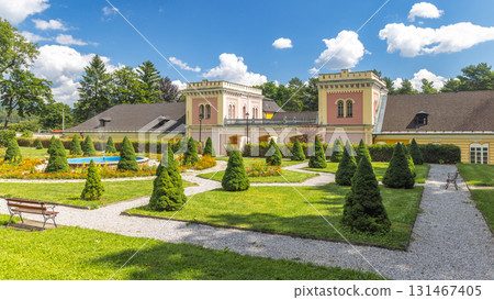 Hodkovce Mansion in Zehra village in Slovakia, Europe. Ornate building with manicured garden, featuring conical trees, gravel pathways, and a central fountain under a sunny sky. Hodkovce Mansion in Zehra village in Slovakia, Europe. Ornate building with manicured garden, featuring conical trees, gravel pathways, and a central fountain under a sunny sky. 131467405