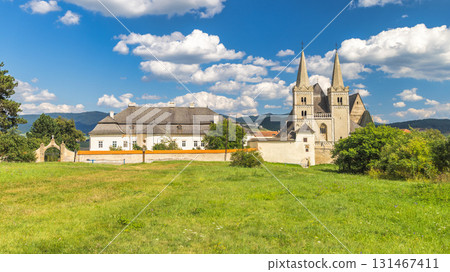 Spisska Kapitula, an ecclesiastical town in region of Spis in Slovakia, Europe. Picturesque European castle and cathedral complex with towers, lush greenery, blue sky, and puffy white clouds. Spisska Kapitula, an ecclesiastical town in region of Spis in Slovakia, Europe. Picturesque European castle and cathedral complex with towers, lush greenery, blue sky, and puffy white clouds. 131467411