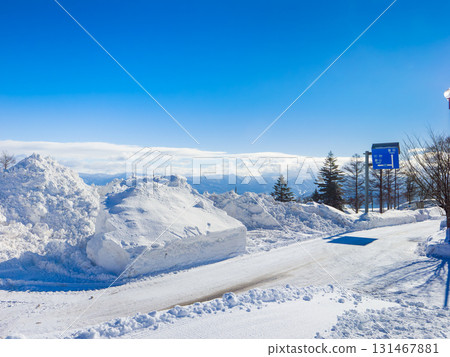 A clear winter day at Madarao Kogen and a snowy road covered with high piles of snow (in front of Madarao Kogen Hotel, Myoko City, Niigata Prefecture) 131467881