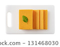 Sheddar cheese slices on a chopping board cutout.  131468030