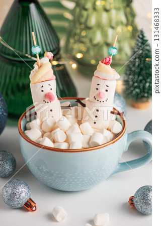 Marshmallow Snowmen in Mug with Christmas Ornaments and Trees Marshmallow Snowmen in Mug with Christmas Ornaments and Trees 131468333