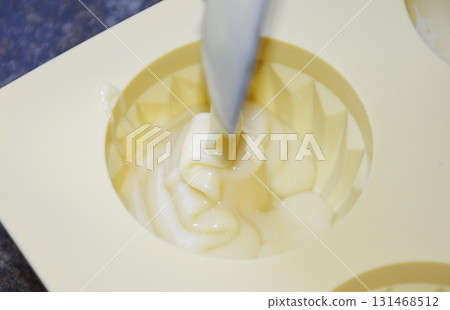 pouring liquid muffin batter into silicone baking mold 131468512