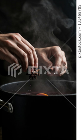 A person's hands carefully add star anise and a cinnamon stick to a dark pot of steaming mulled wine, showcasing an orange slice in the rich red liquid against a moody dark background. A person's hands carefully add star anise and a cinnamon stick to a dark pot of steaming mulled wine, showcasing an orange slice in the rich red liquid against a moody dark background. 131468785