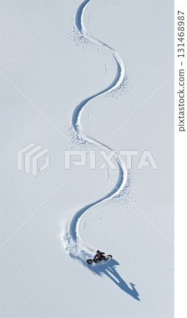 An aerial perspective showcases a person riding a specialized fat bike, carving an elegant S-shaped trail across a pristine white snowfield under clear winter sunlight. An aerial perspective showcases a person riding a specialized fat bike, carving an elegant S-shaped trail across a pristine white snowfield under clear winter sunlight. 131468987