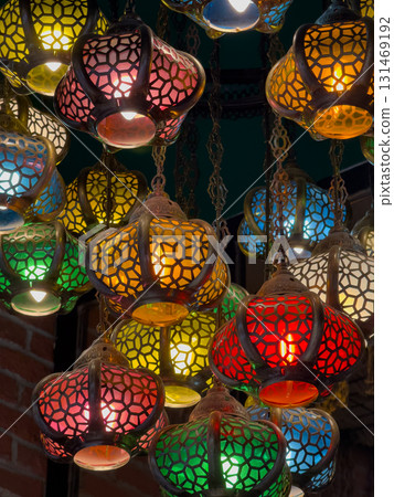 Colorful mosaic lanterns hanging from chains create vibrant warm glow in a busy decor scene Colorful mosaic lanterns hanging from chains create vibrant warm glow in a busy decor scene 131469192
