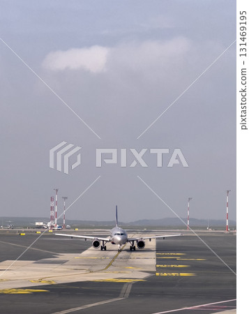 Commercial airplane taxiing on an airport runway under cloudy sky Commercial airplane taxiing on an airport runway under cloudy sky 131469195