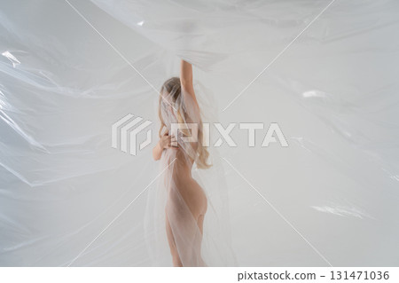 Blonde woman posing gracefully with delicate fabric in a beauty studio 131471036