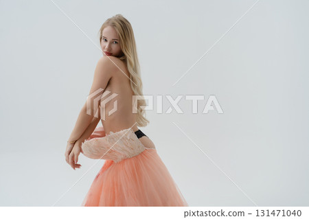 Elegant blonde woman poses in a stunning studio setting with flowing fabric 131471040