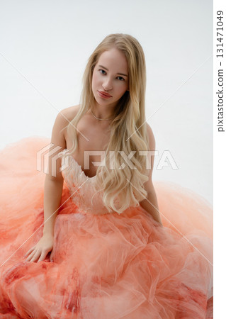 Blonde woman embodies elegance in a stunning pastel gown in studio setting 131471049
