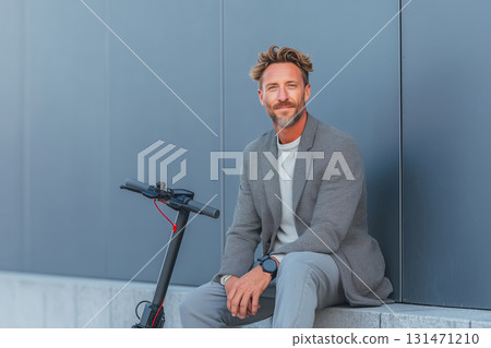 Smiling young businessman enjoying a moment on his electric scooter outdoors 131471210