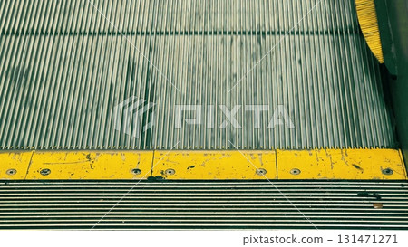 Detailed close-up view of escalator steps with a worn yellow safety marking. Concept of urban transport, mobility, technology, and safety Detailed close-up view of escalator steps with a worn yellow safety marking. Concept of urban transport, mobility, technology, and safety 131471271