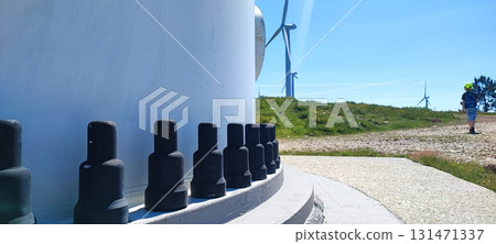 Industrial bolts on the base of a wind turbine with blades in the background. Concept of renewable energy, sustainable development, and eco-friendly technologies. 131471337